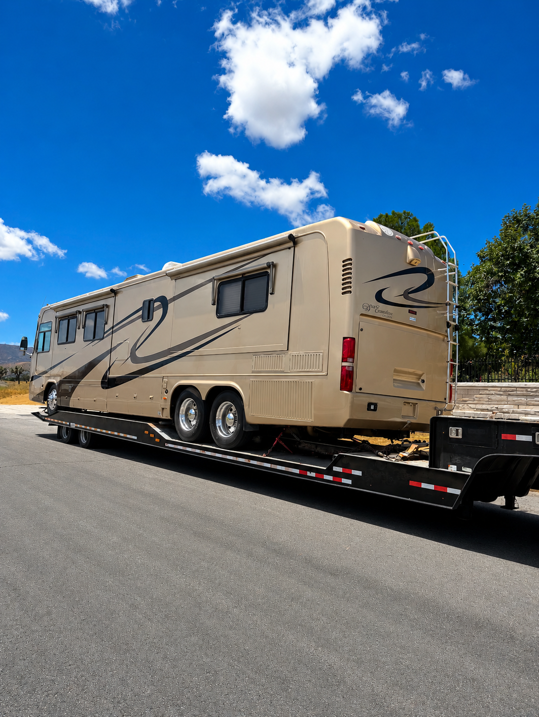 Tan luxury motorhome secured on a Johnny's Lightning Transportation flatbed trailer, side profile